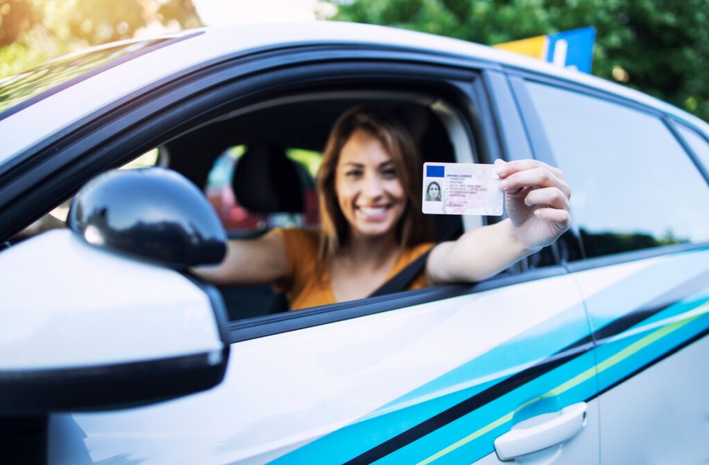 A happy driver holds out their driver's license.