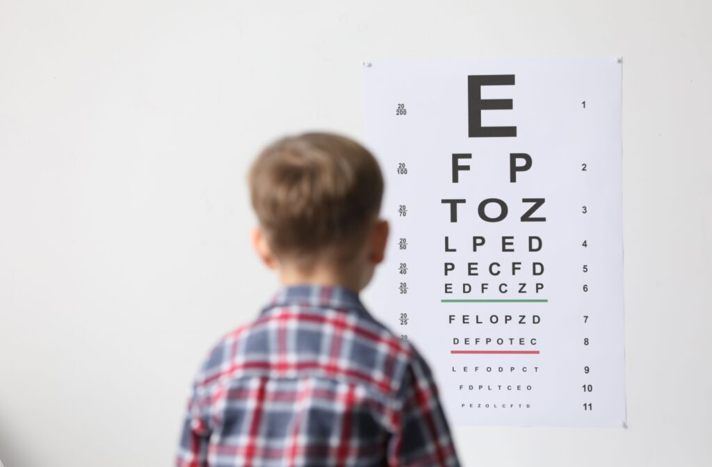 A child reading an eye chart at an optometrist's office, monitoring for warning signs of myopia.